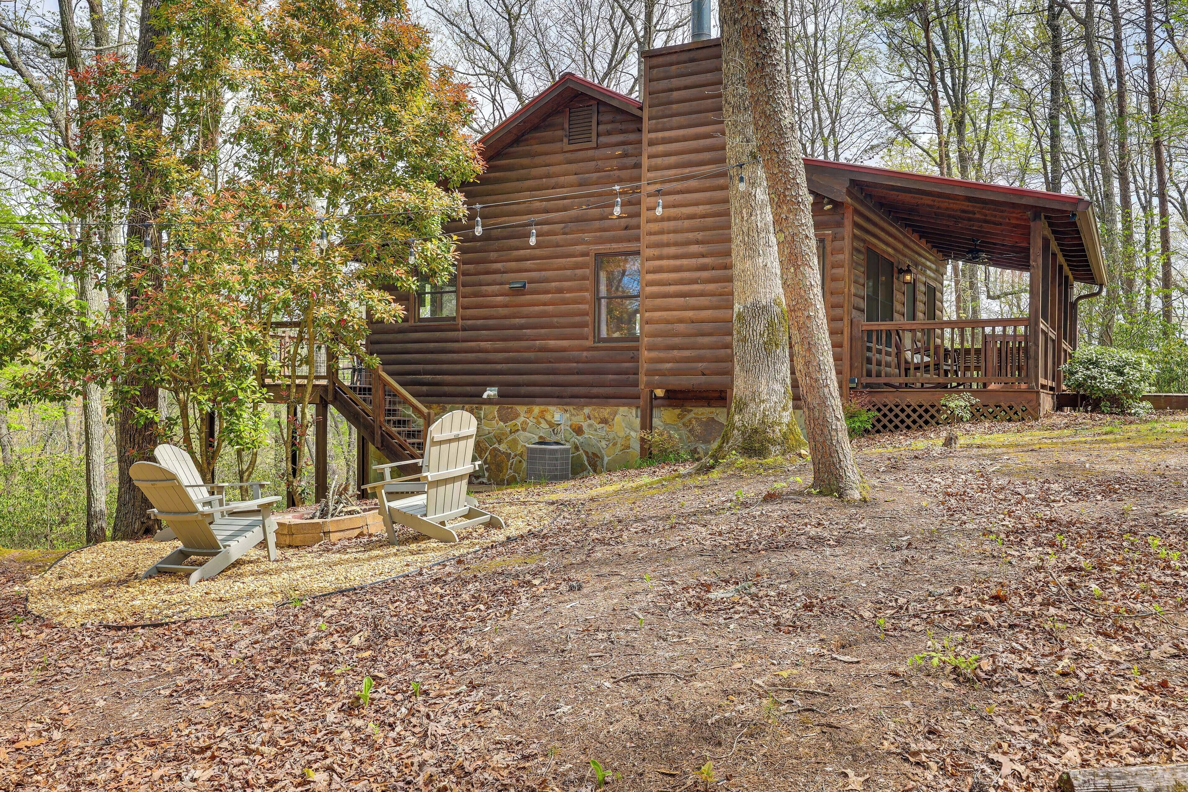 A rustic cabin with a porch, surrounded by trees and a leaf-covered ground.