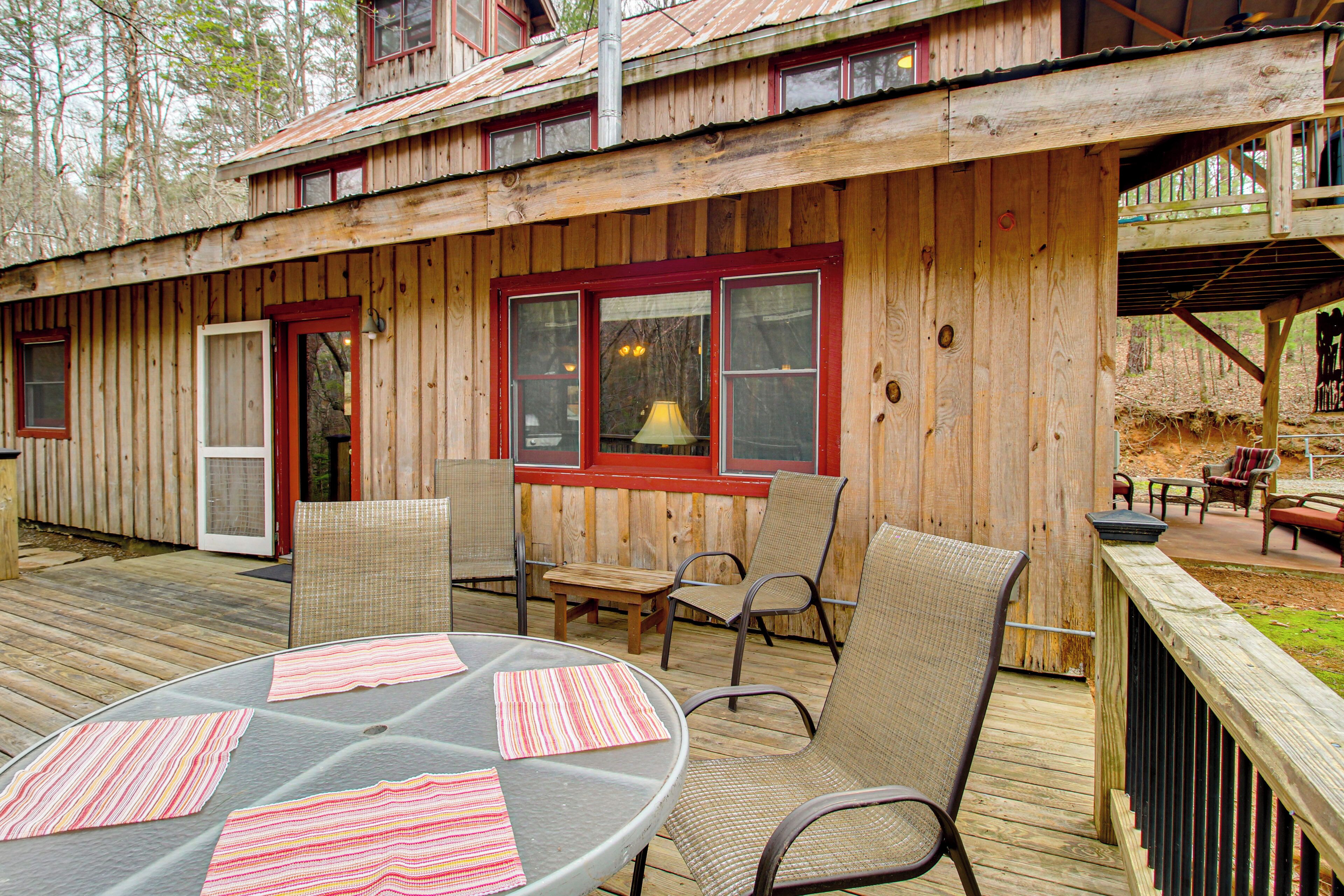 A wooden cabin with a deck, outdoor seating, and a table with placemats.