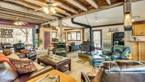 Un interior rústico con muebles de cuero, chimenea y vigas de madera a la vista.