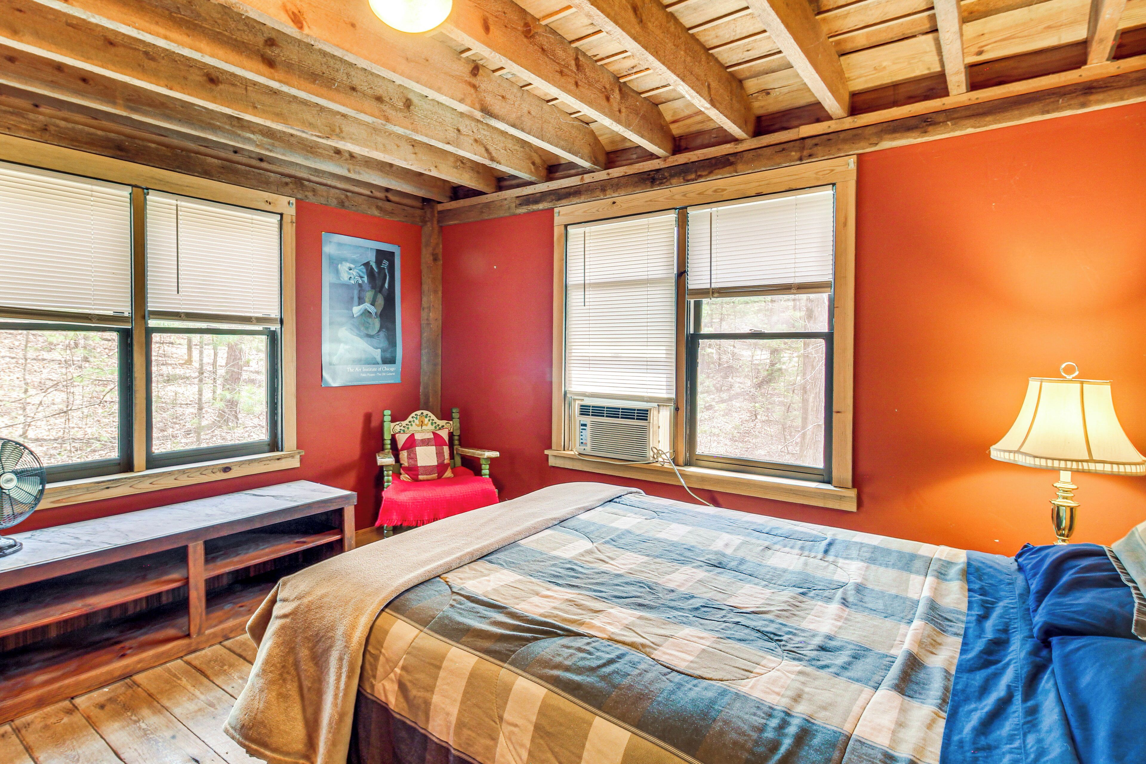 A bedroom with a bed, a bench, and a window with blinds.