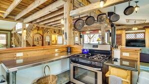 Una cocina r ústica con paredes de madera, una estufa y ollas colgantes.
