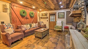 A cozy living room with a wooden ceiling, a brown sofa set, a coffee table, and a stone fireplace. - Tubes & Kayaks: 5-acre North Georgia Mtn Retreat (Sautee Nacoochee)