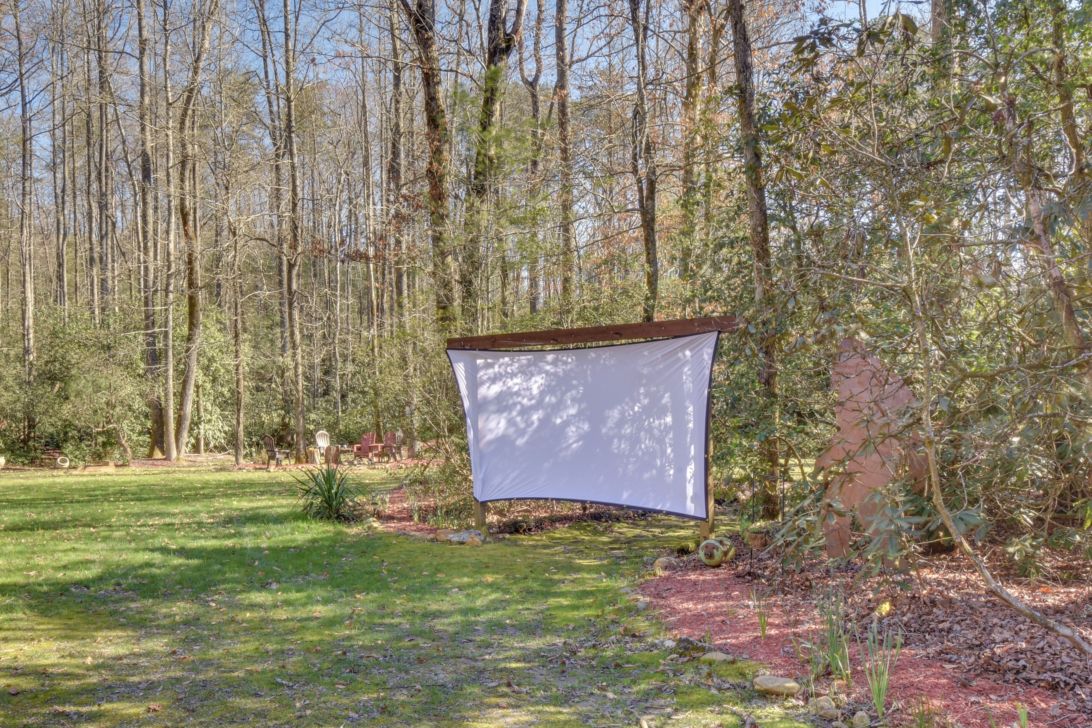 A tent-like structure in a forested area with a grassy foreground and trees in the background.