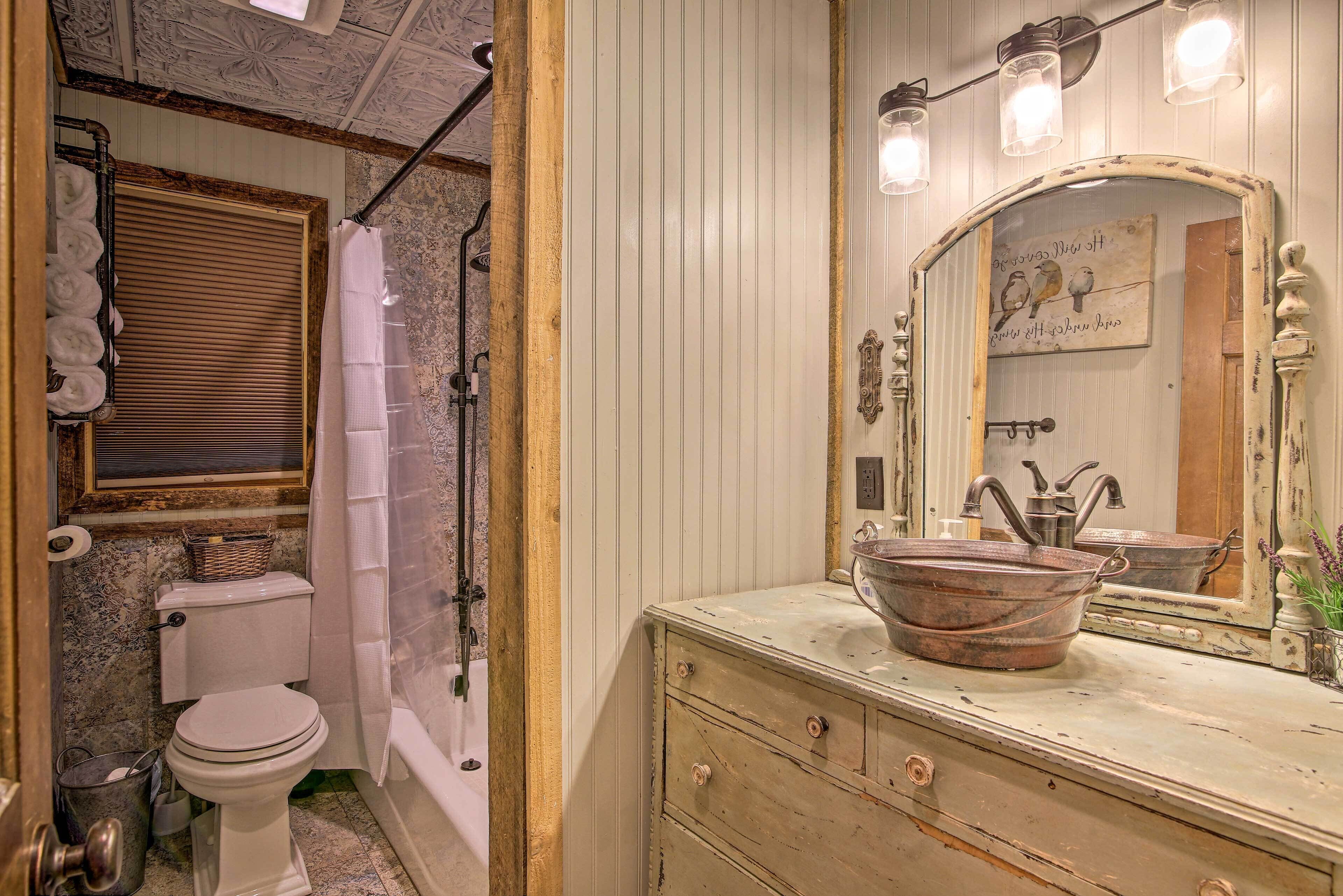 A bathroom with a toilet, a shower curtain, a sink with a mirror, and a decorative wall.