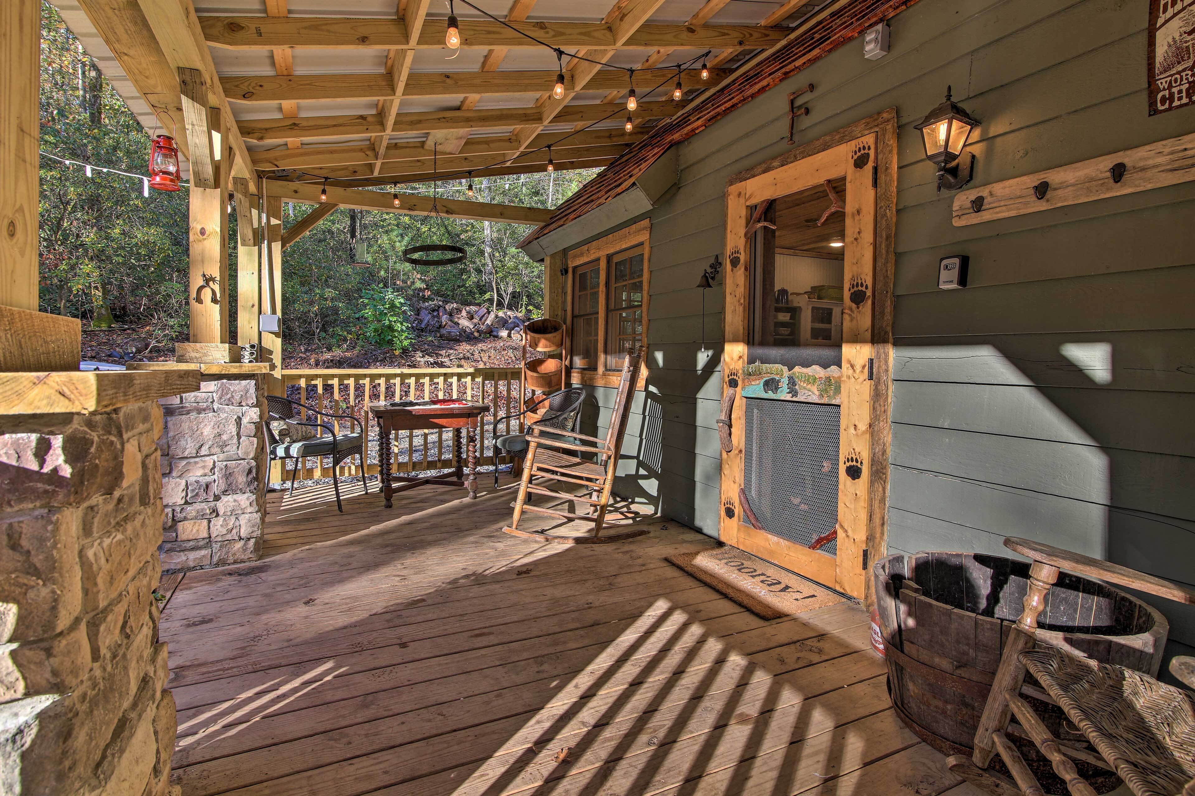 A wooden porch with a stone wall, a wooden table, and a rocking chair.