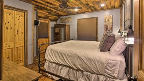 A bedroom with a wooden ceiling, a bed with a white bedspread, a wooden wardrobe, and a wall-mounted TV. - Tubes & Kayaks: 5-acre North Georgia Mtn Retreat (Sautee Nacoochee)