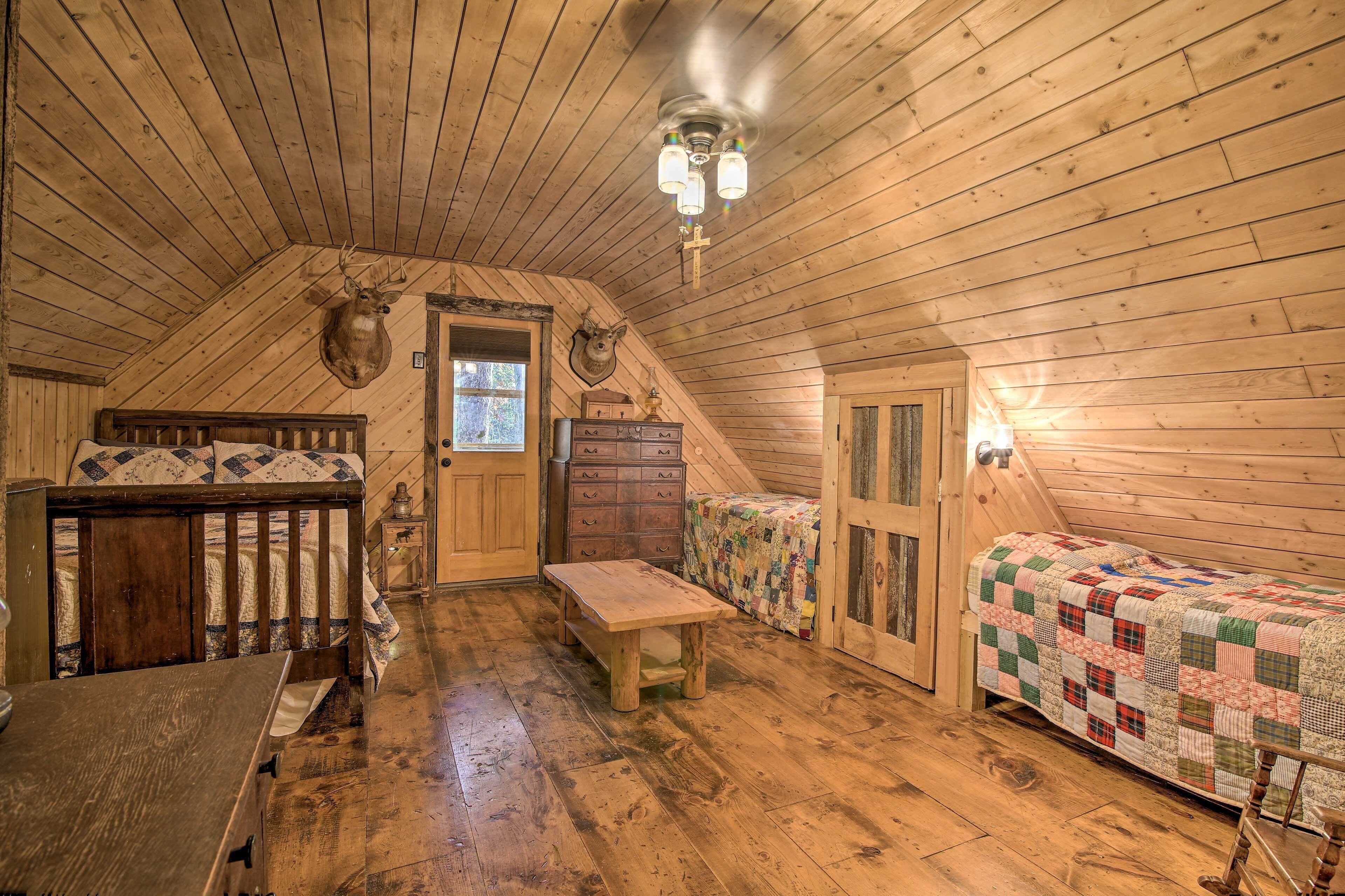 Une chambre confortable située dans les combles, avec des murs en bois, un lit en bois, un banc, une commode et une couvre-lit matelassé.