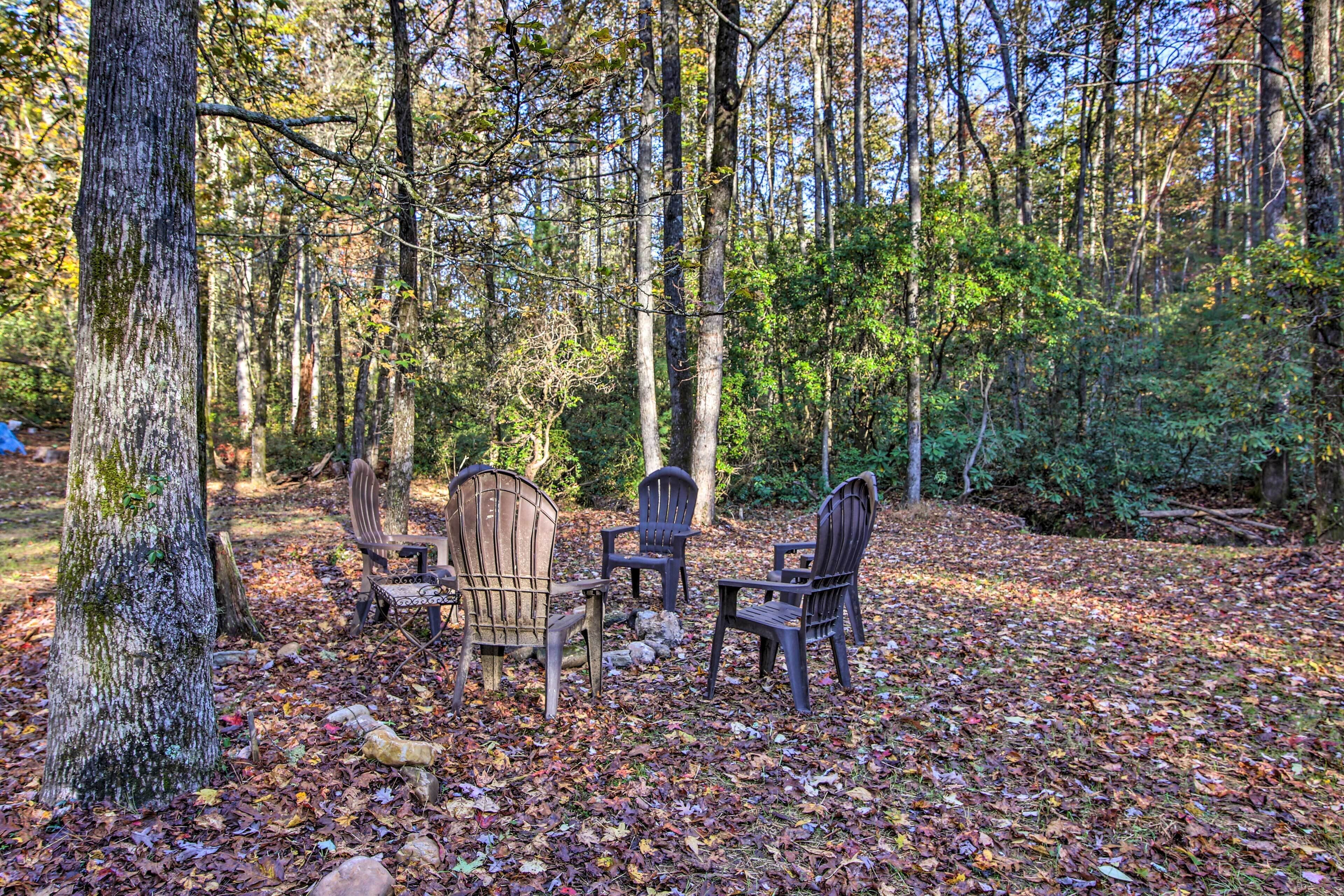 A forest clearing with a wooden table and four chairs.
