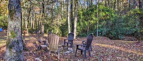A forest clearing with a wooden table and four chairs.
