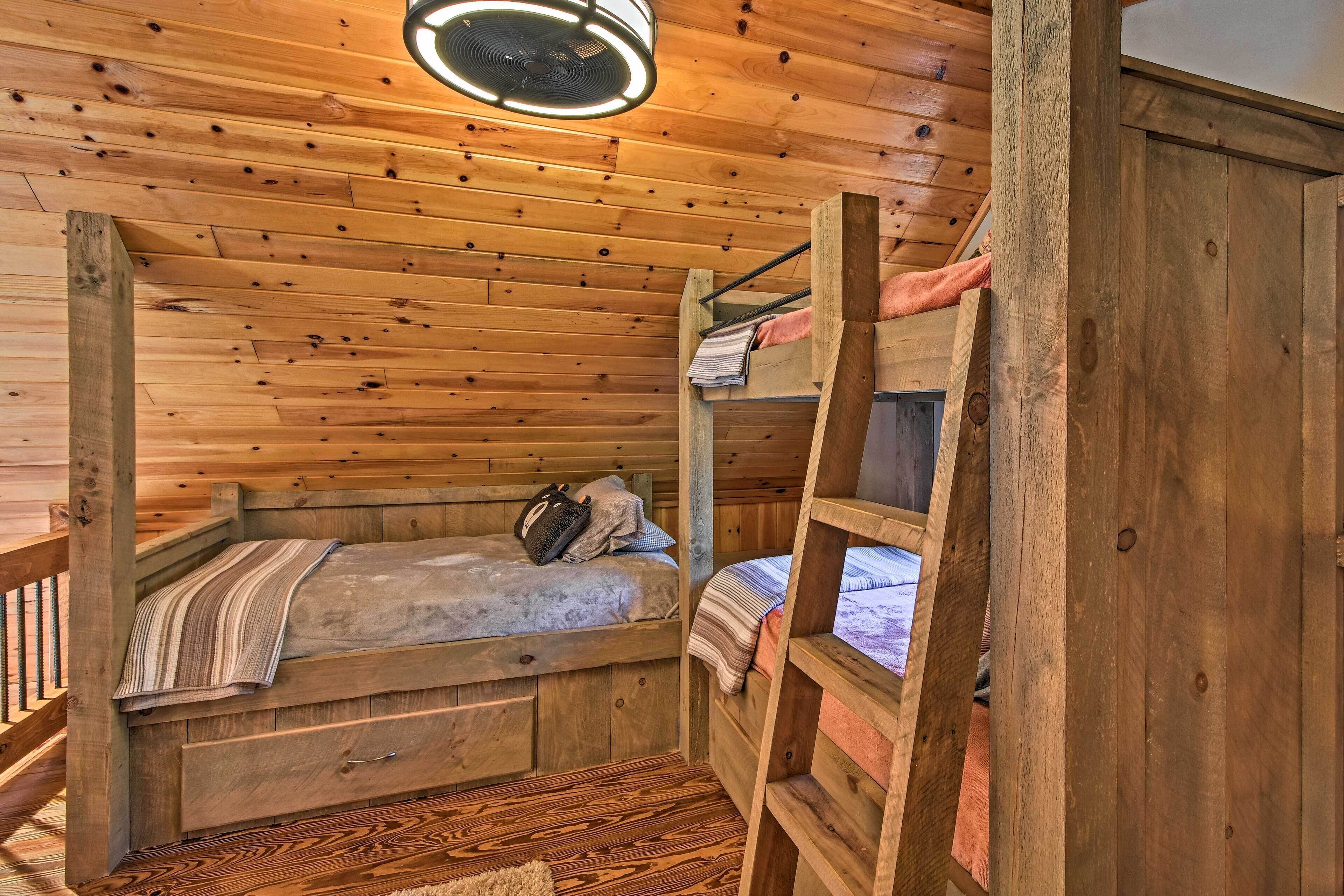 Ein Zimmer in einer Holzhütte mit Etagenbetten, einem Deckenventilator und einem kleinen Fenster.