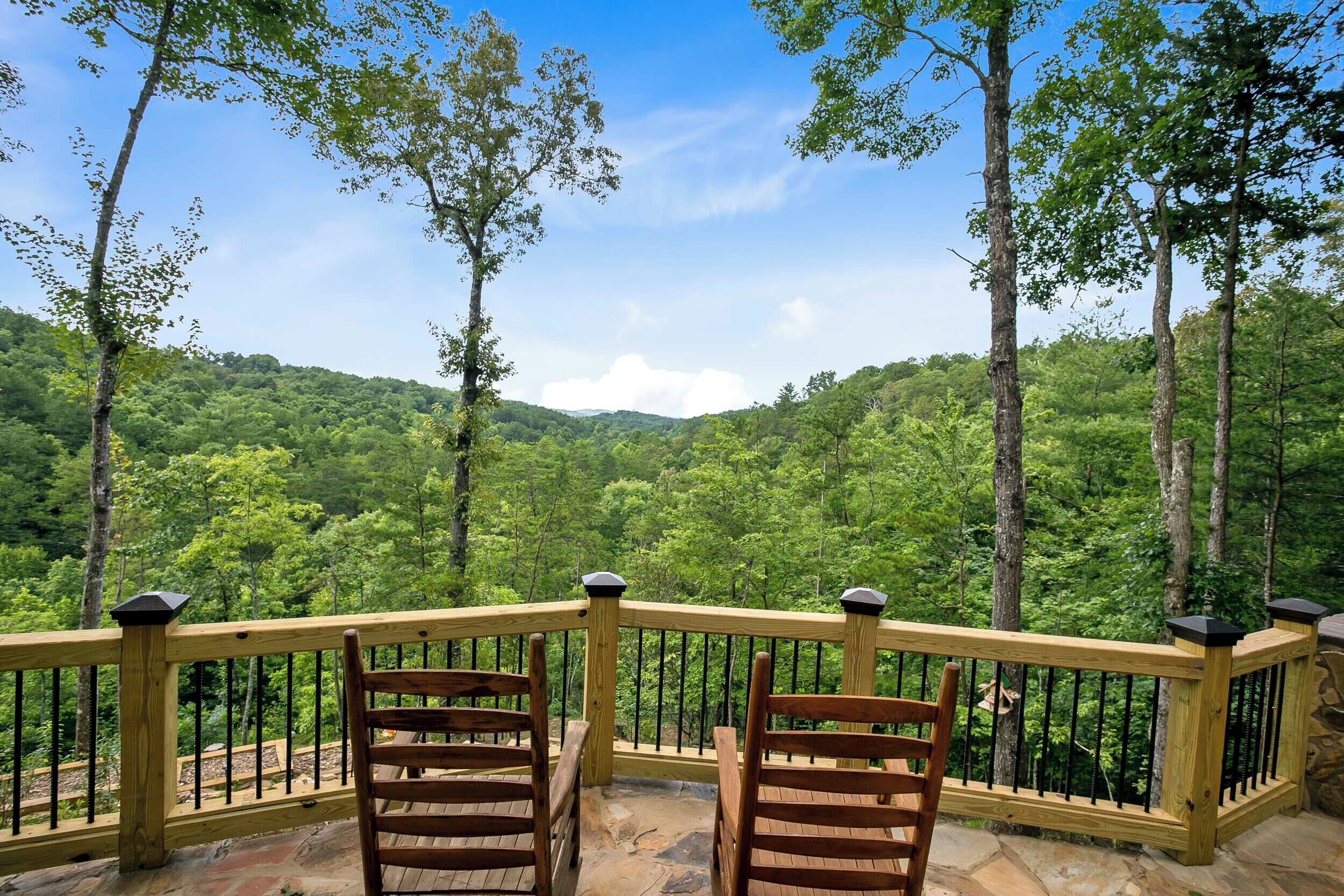 A wooden deck with a railing overlooking a forested valley.