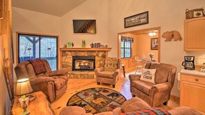A cozy cabin interior with a stone fireplace, plush seating, and a dining area. - Modern Cabin w/ Deck in the Blue Ridge Mountains! (Blairsville)