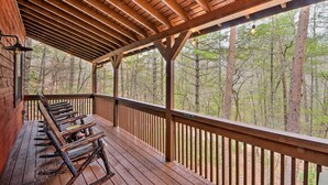 A wooden deck with benches, a railing, and a view of a forest. - Modern Cabin w/ Deck in the Blue Ridge Mountains! (Blairsville)