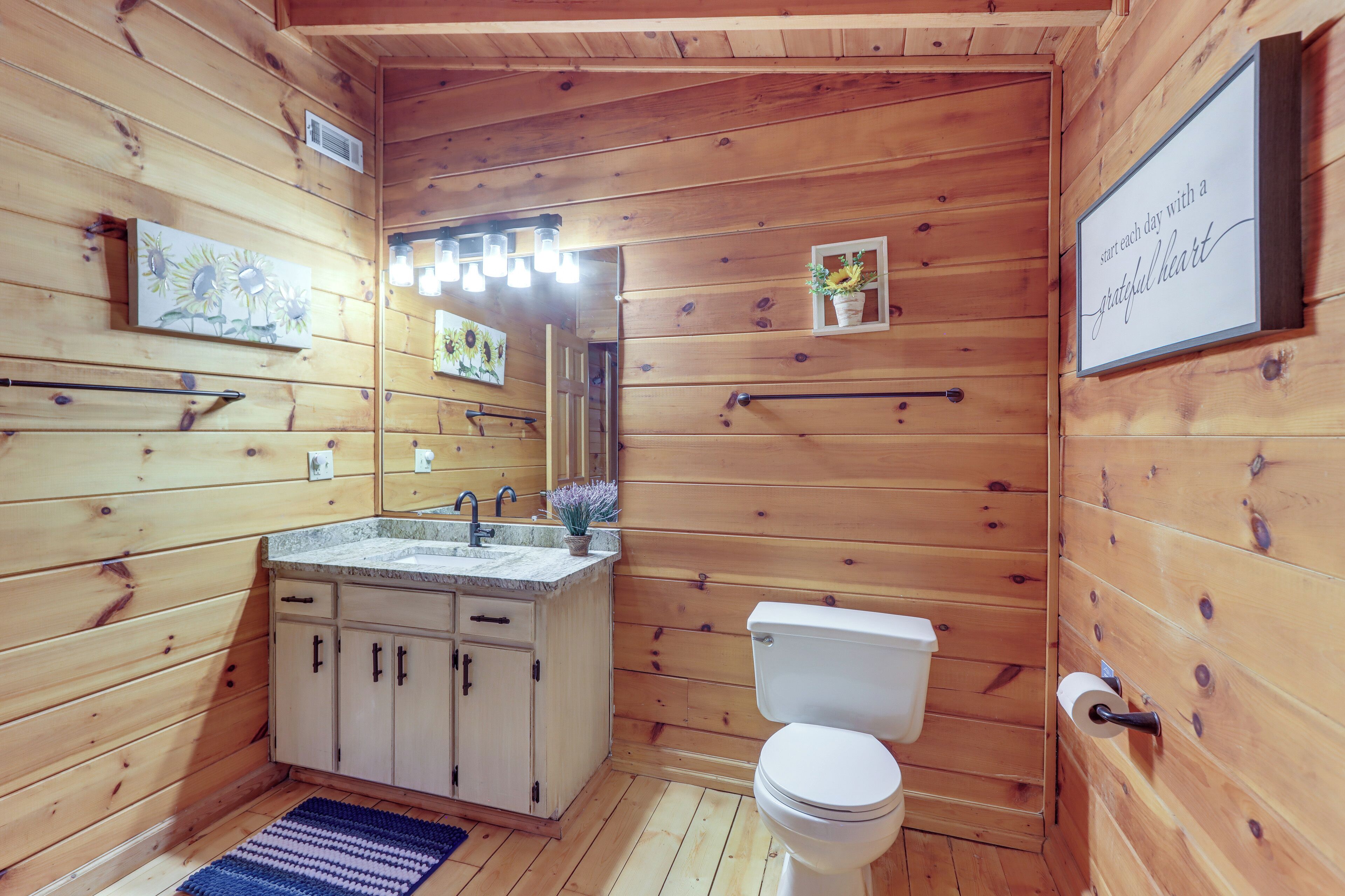 A wooden cabin bathroom with a sink, toilet, and a motivational quote on the wall.