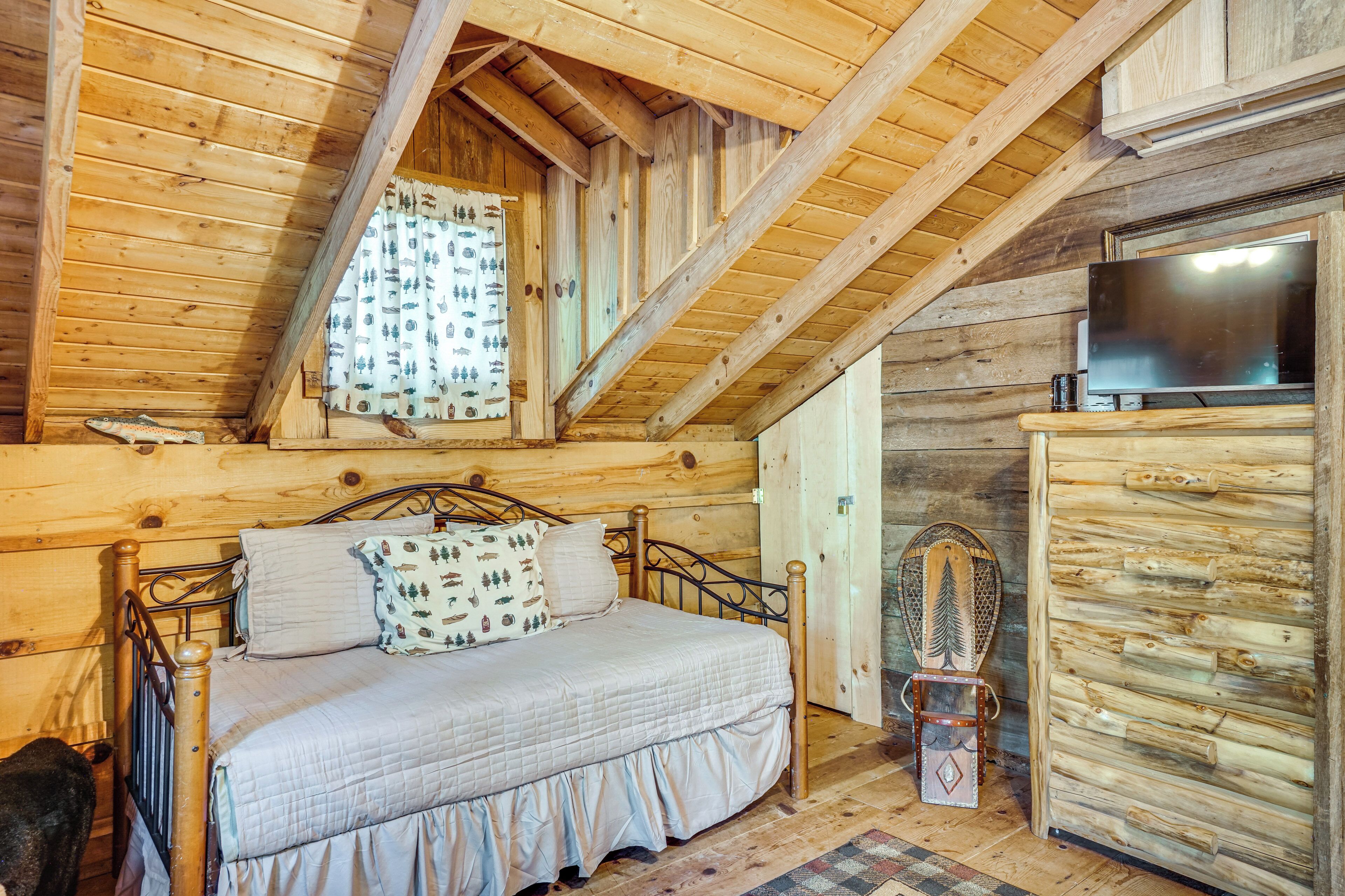 A wooden cabin room with a bed, a television, and a rustic decor.