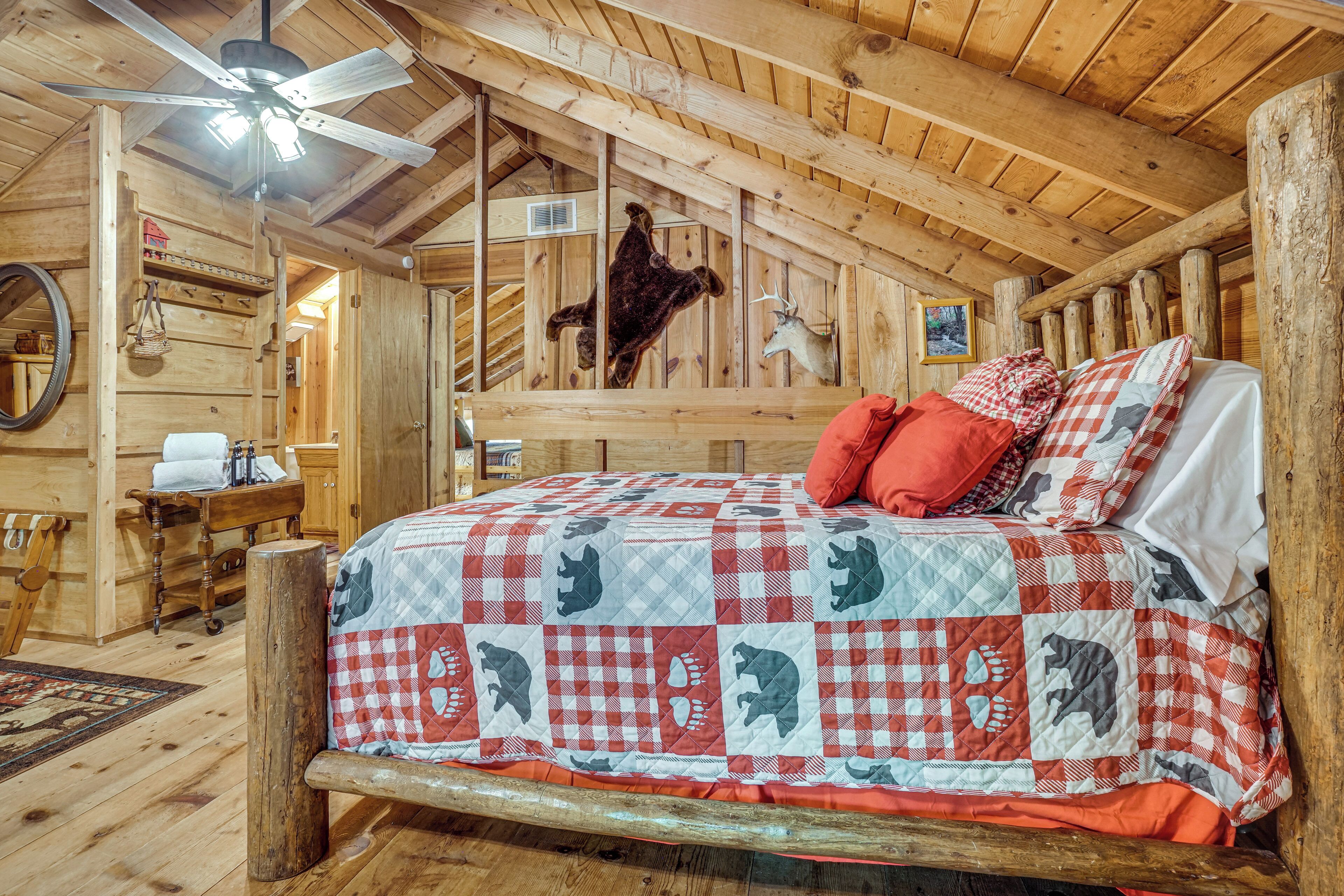 A rustic wooden room with a bed featuring a checkered quilt, a ceiling fan, and wooden beams.