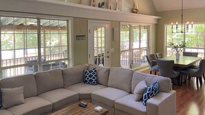 A modern living room with a sectional sofa, a wooden coffee table, and a dining area with a table and chairs. - Lakefront House With Private Dock + Fire Pit! (Eatonton)