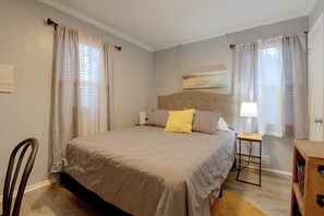 A bedroom with a bed, a bedside table, a chair, and a painting on the wall. - Hampton Vacation Rental: Central Location, Patio (Hampton)