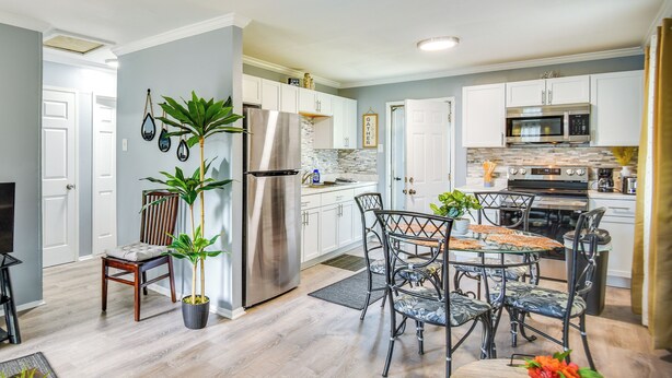 A modern kitchen with white cabinets, stainless steel appliances, and a dining area with a metal table and chairs. - Hampton Vacation Rental: Central Location, Patio (Hampton)