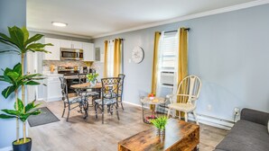 A modern living room with a wooden coffee table, a gray sofa, and a dining area with a chandelier. - Hampton Vacation Rental: Central Location, Patio (Hampton)