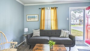 A living room with a grey sofa, wooden coffee table, and a framed picture on the wall. - Hampton Vacation Rental: Central Location, Patio (Hampton)