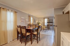 A dining area with a wooden table and chairs, a sofa, and a refrigerator. - Hampton Vacation Rental: Central Location, Patio (Hampton)