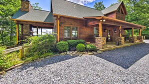 A rustic cabin with a stone foundation, wooden exterior, and a covered porch. - Unique Mineral Bluff Home With Mountain Views! (Mineral Bluff)