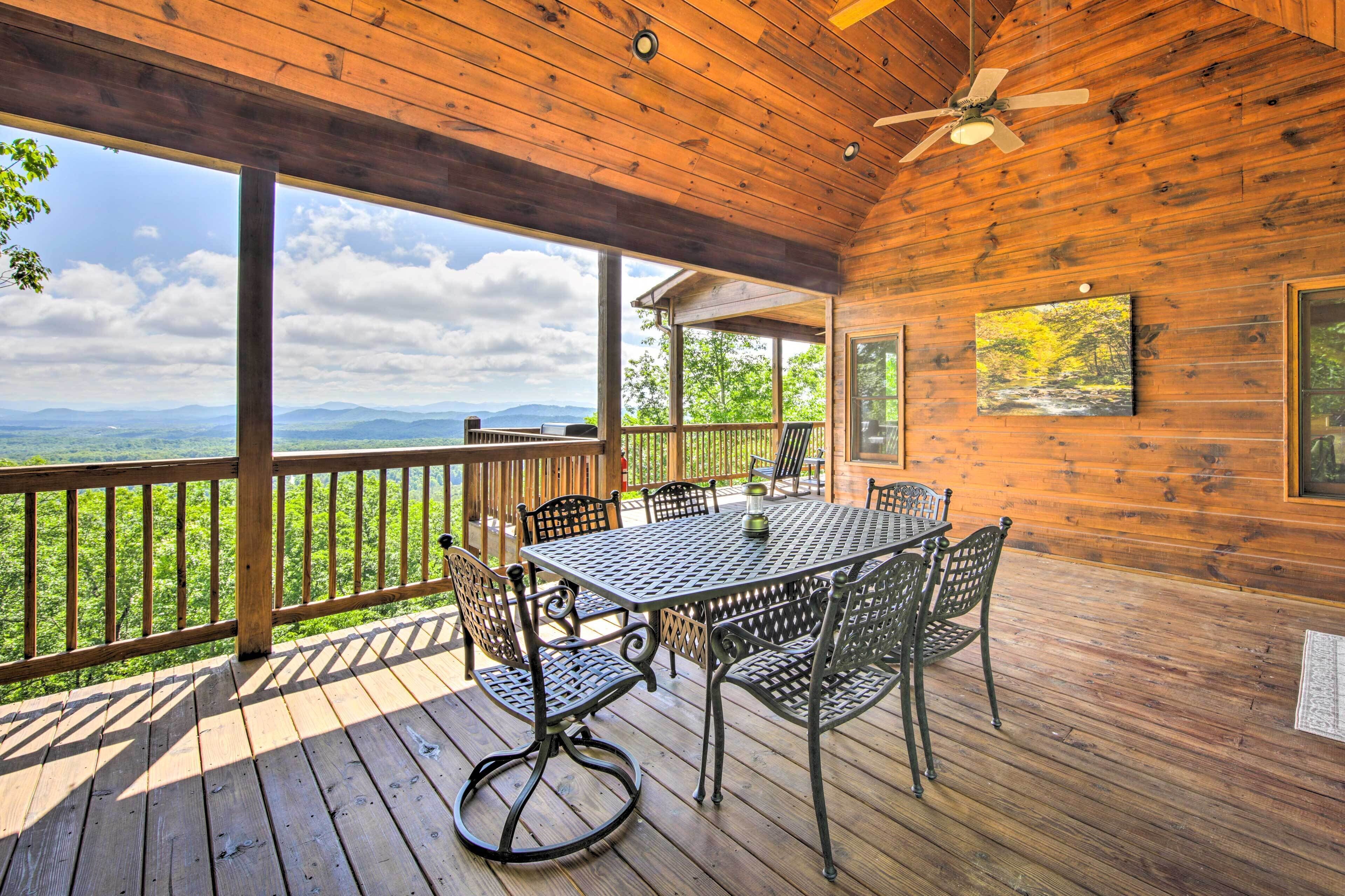 Una terraza de madera con mesa y sillas, con vistas a un paisaje pintoresco.