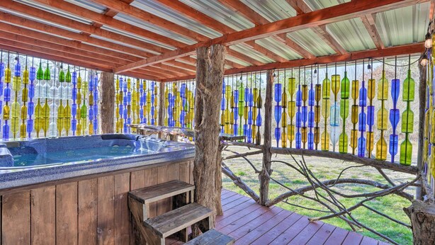 A wooden deck with a hot tub, surrounded by a fence decorated with colorful glass bottles. - Charming Escape w/ Fire Pit in Summerville! (Summerville)