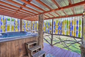 A wooden deck with a hot tub, surrounded by a fence decorated with colorful glass bottles. - Charming Escape w/ Fire Pit in Summerville! (Summerville)