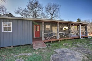 A rustic cabin with a wooden deck, a red door, and a small porch area. - Charming Escape w/ Fire Pit in Summerville! (Summerville)