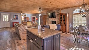 A spacious living area with a fireplace, a dining table with chairs, a kitchen island, and a ceiling fan. - Charming Escape w/ Fire Pit in Summerville! (Summerville)