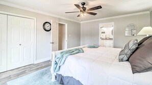 Ein Schlafzimmer mit Bett, Deckenventilator, einer Uhr und einer Tür.