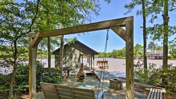 A wooden deck with a swing, a covered seating area, and a view of a body of water.