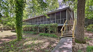 A modern house with large windows, a wooden deck, and a staircase leading to a deck area.
