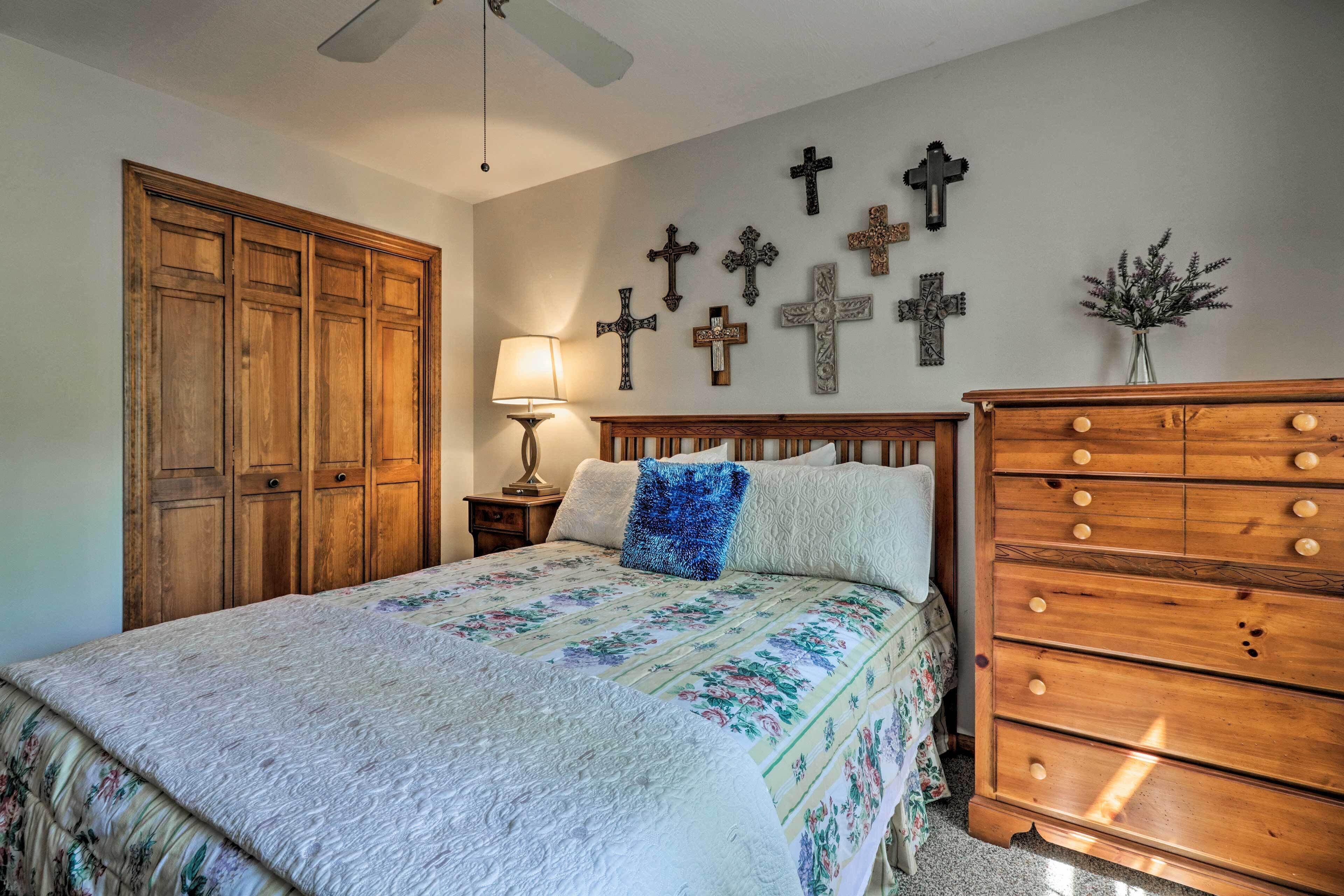 Un dormitorio con cama, cómoda de madera y cruces colgadas en la pared.