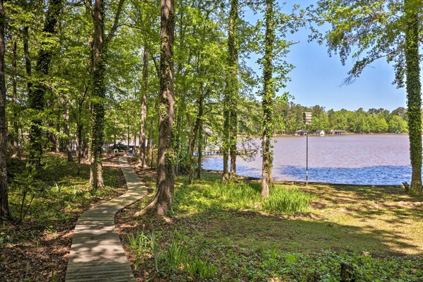 A wooden pathway leading to a lakeside area with trees and a dock. - Lakefront Milledgeville Cabin: Private Dock, Porch (Milledgeville)