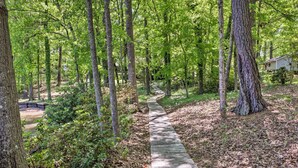 A wooden pathway through a forested area with a house in the background.