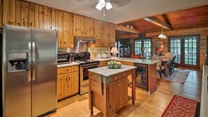 A spacious kitchen with wooden cabinets, a stainless steel refrigerator, a central island, and a ceiling fan.