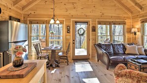 L’intérieur d’un chalet en bois comprend un coin repas, un salon avec un canapé en cuir et une cuisine équipée d’un réfrigérateur.