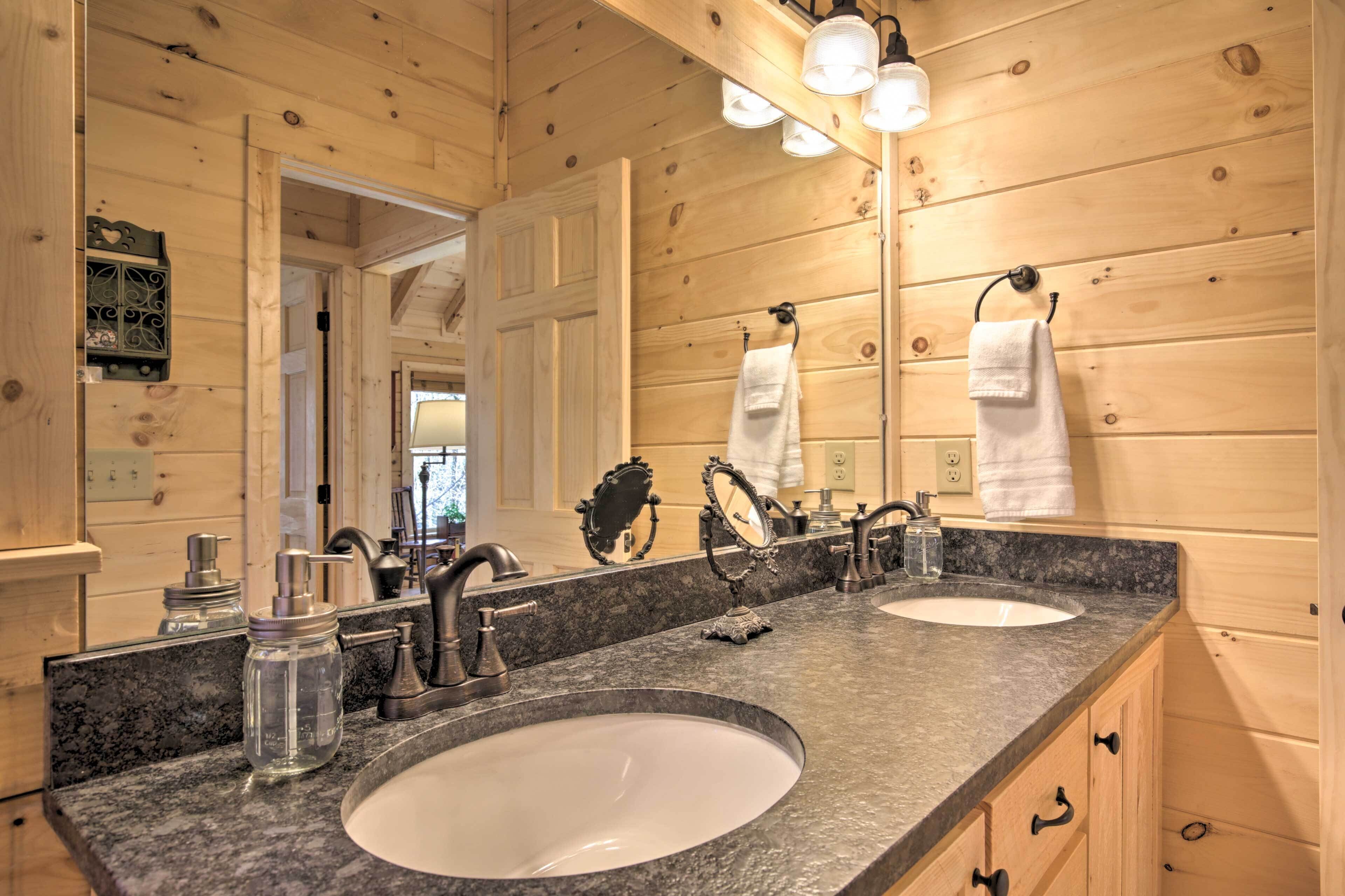 Un baño de cabaña de madera con dos lavamanos, un espejo grande y un tocador con cajones.