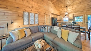 A cozy cabin interior with a large sectional sofa, a dining area, and a kitchen. - Blue Ridge Hideaway w/ Fire Pit & Mtn Views! (Blue Ridge)