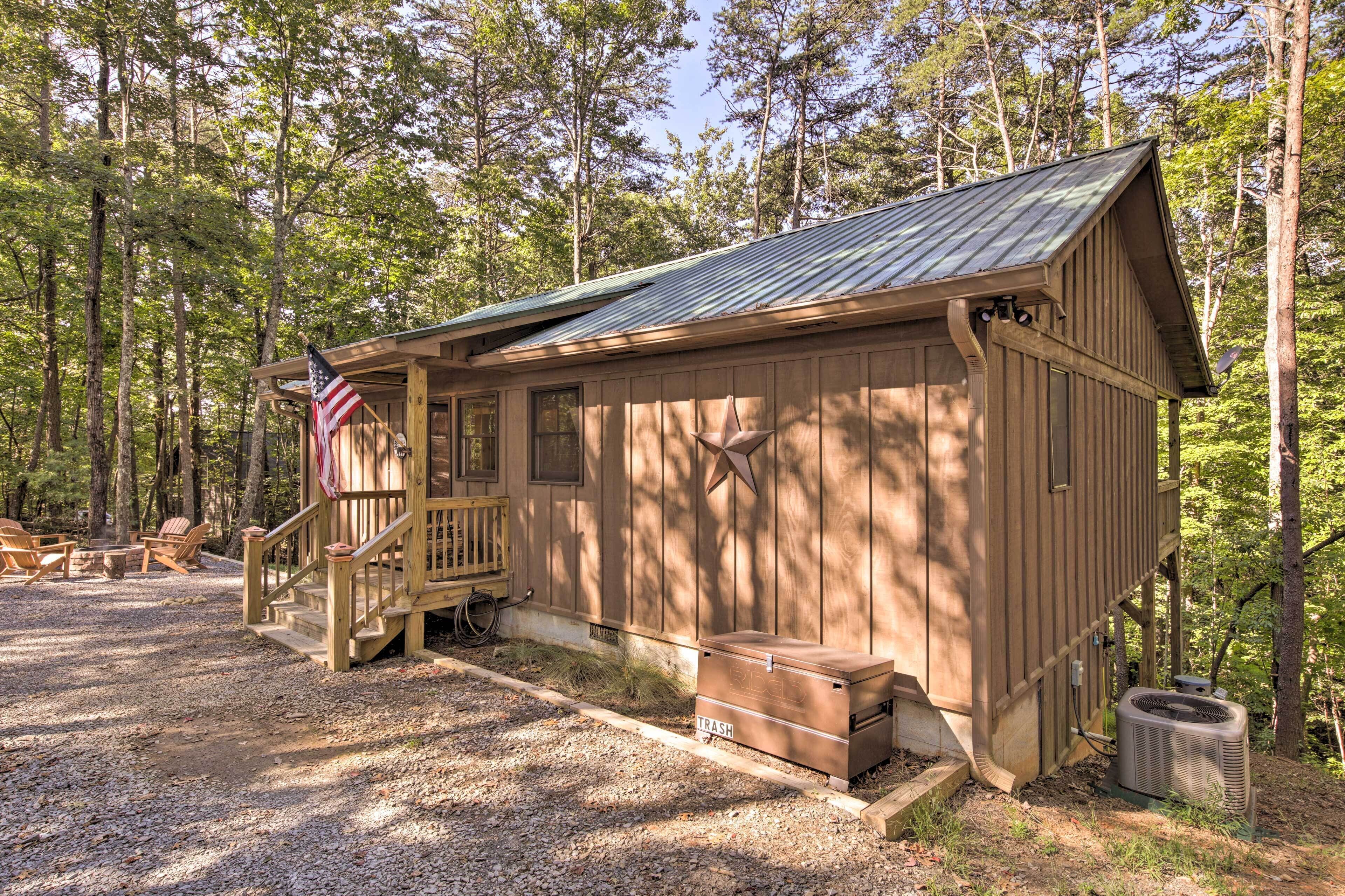 A wooden cabin with a porch, a flag, and a trash bin.