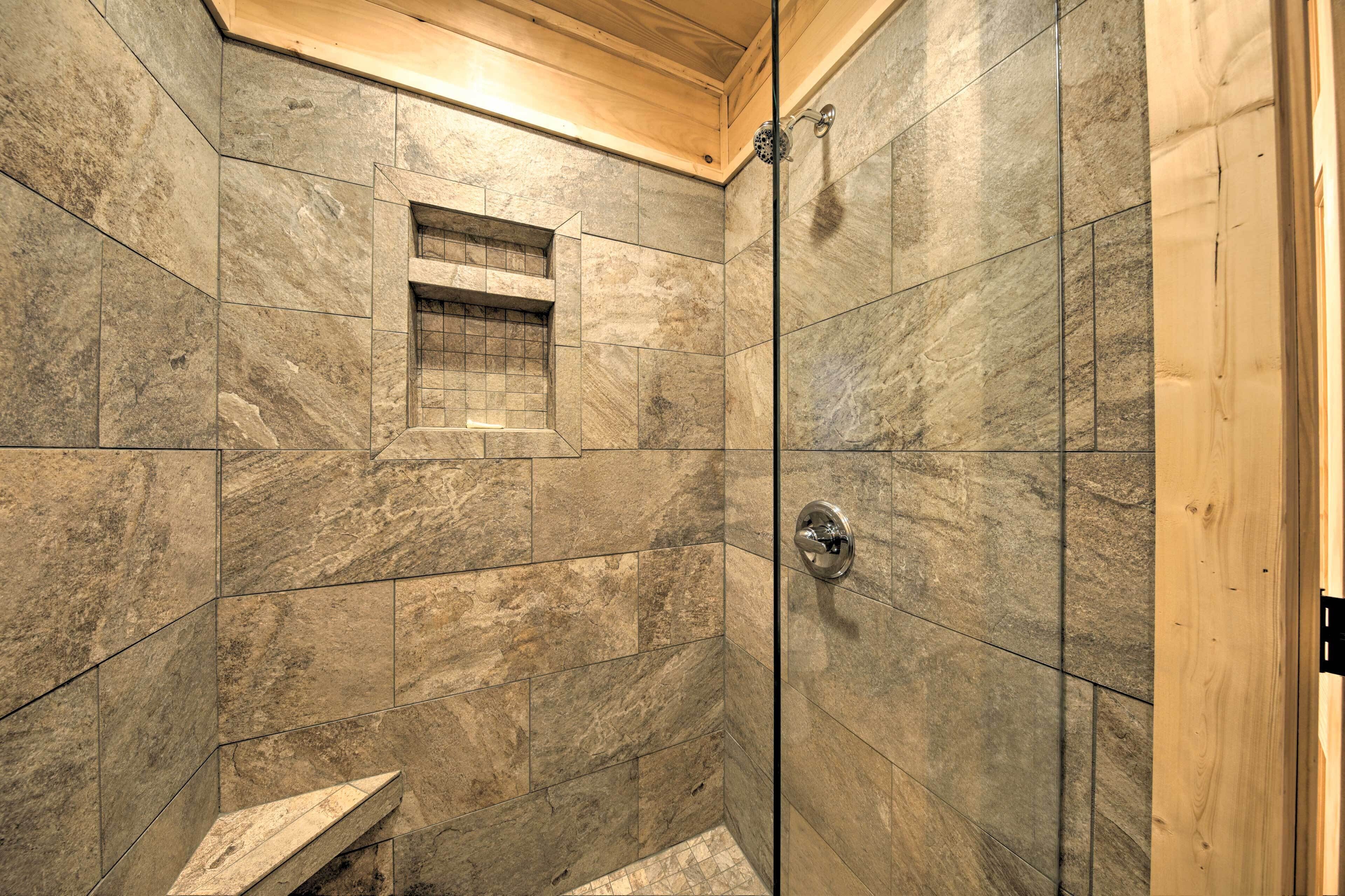 A shower with stone tiles and a wooden ceiling.
