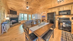 A wooden cabin interior with a dining area, kitchen, fireplace, and large windows. - Blue Ridge Hideaway w/ Fire Pit & Mtn Views! (Blue Ridge)
