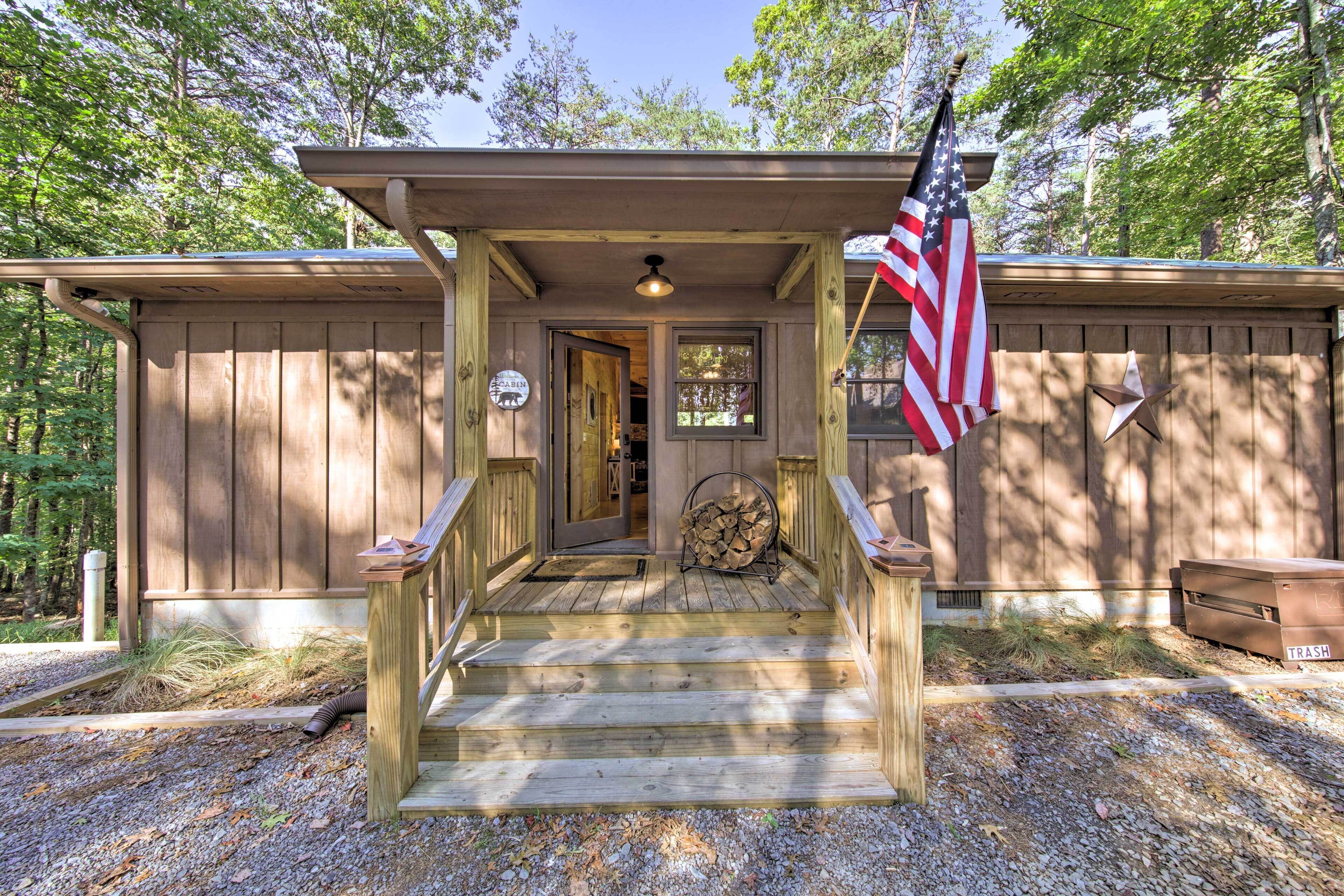 Una baita di legno con un portico, una bandiera americana e un cartello che indica l'accesso agli animali domestici.