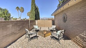 An outdoor patio area with a fire pit, four chairs, and a decorative wall. - Fire Pit & Grill! Tucson Family Home, Walk to Park (Tucson)