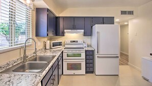 A modern kitchen with a stainless steel sink, double ovens, a microwave, and a refrigerator. - Fire Pit & Grill! Tucson Family Home, Walk to Park (Tucson)