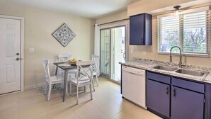 A kitchen with a dining area, a dishwasher, and a window with blinds. - Fire Pit & Grill! Tucson Family Home, Walk to Park (Tucson)