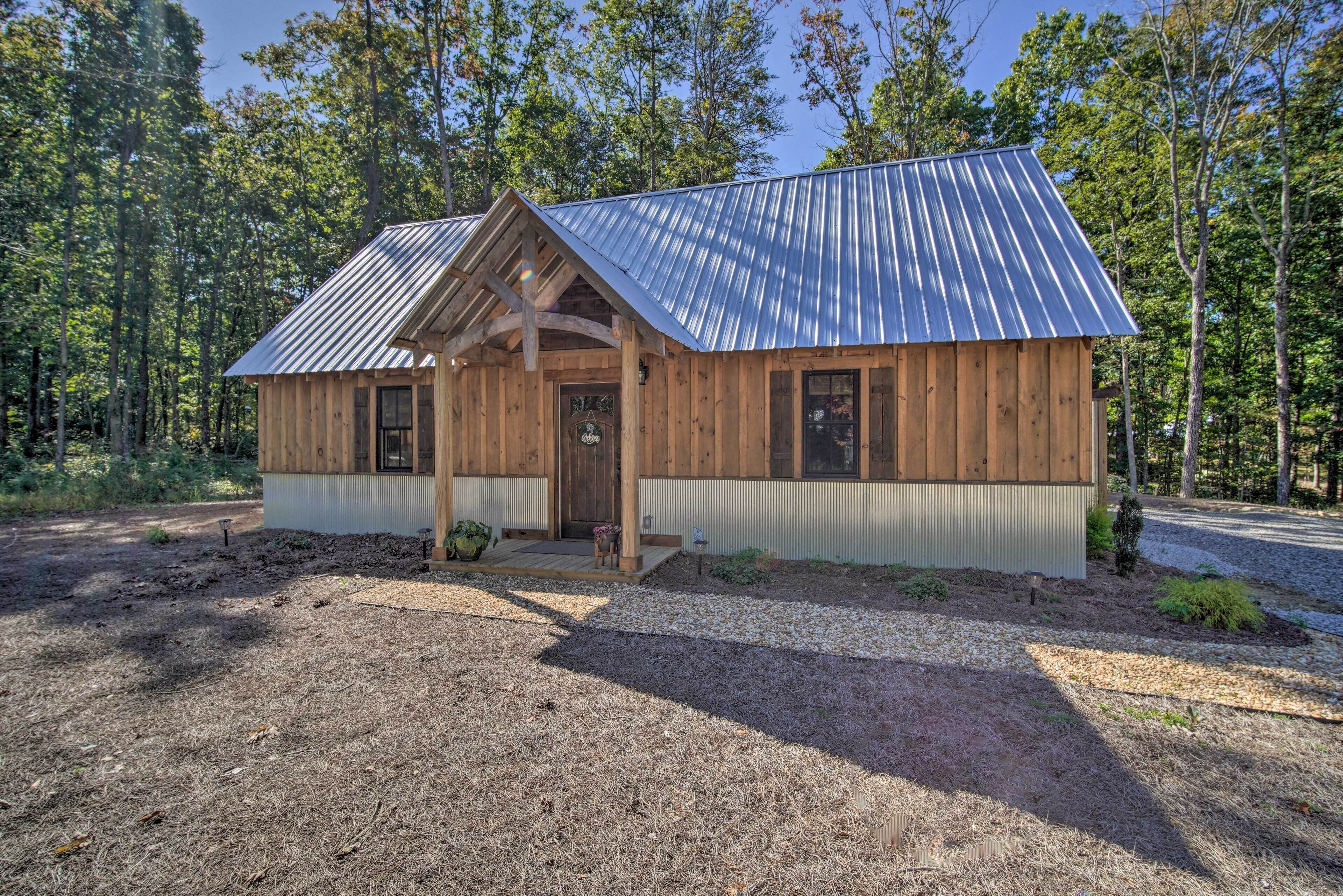 A wooden cabin with a metal roof, surrounded by trees.